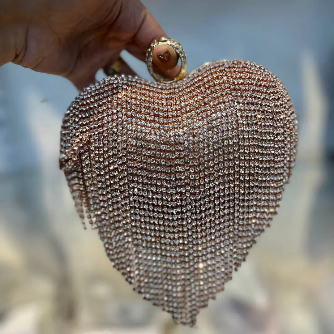 Heart-shaped beaded clutch held by a hand with a blurred natural background