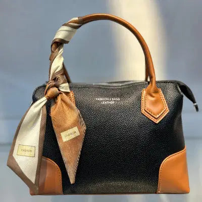 Black and brown handbag with a visible brand label on a reflective surface