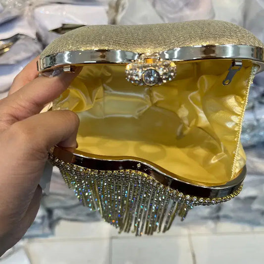 Gold clutch with decorative elements held by a hand against a blurred background